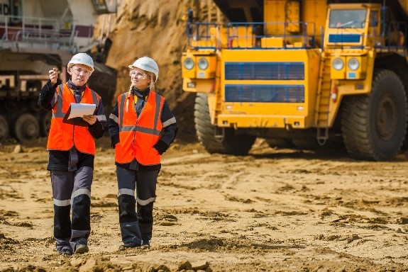 Sept two people in orange hi vis vests and white hard hats with truck