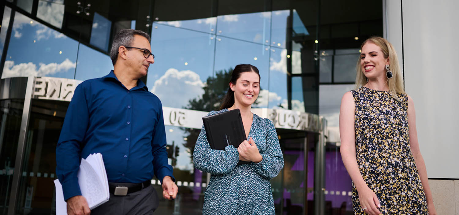 Three people walking outside of a building