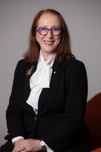 Studio photograph of Professor Rosalind Croucher AM seated and smiling at the camera.