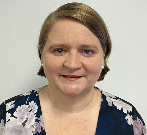 Noni Ryan, the Employment Facilitator for Fitzroy stands in-front of a blank white wall smiling at the camera..