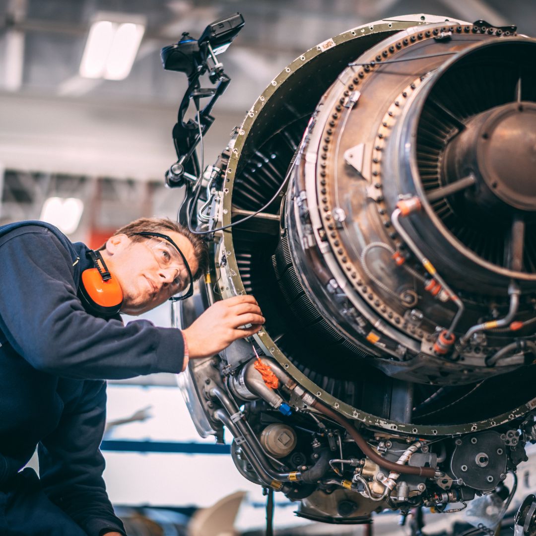 Person in mechanics outfit looking at an engine