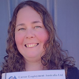 Mid-close up of Kira-lee facing the camera, grinning proudly while holding up a certificate document.