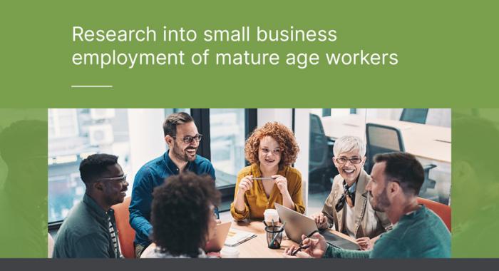 Six office workers enjoying a discussion while seated around a circular table. The caption positioned to the left reads: "Research into small business employment of mature age workers".