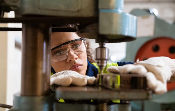 Person wearing safety goggles using an industrial drill press 