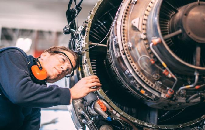 Person in mechanics outfit looking at an engine